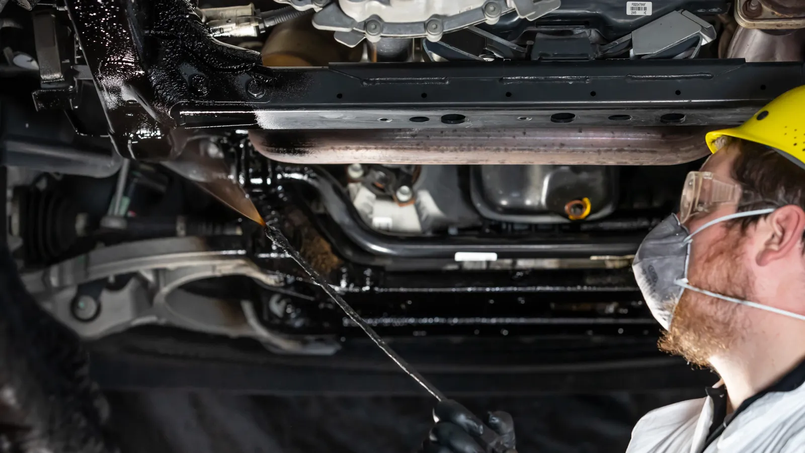 Mobile Rust Doctor technician applying Bilt Hamber Dynax underseal to a vehicle underbody