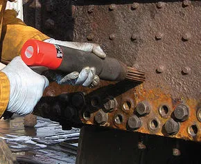 Loose rust being mechanically de-scaled from a vehicle underbody back to sound metal